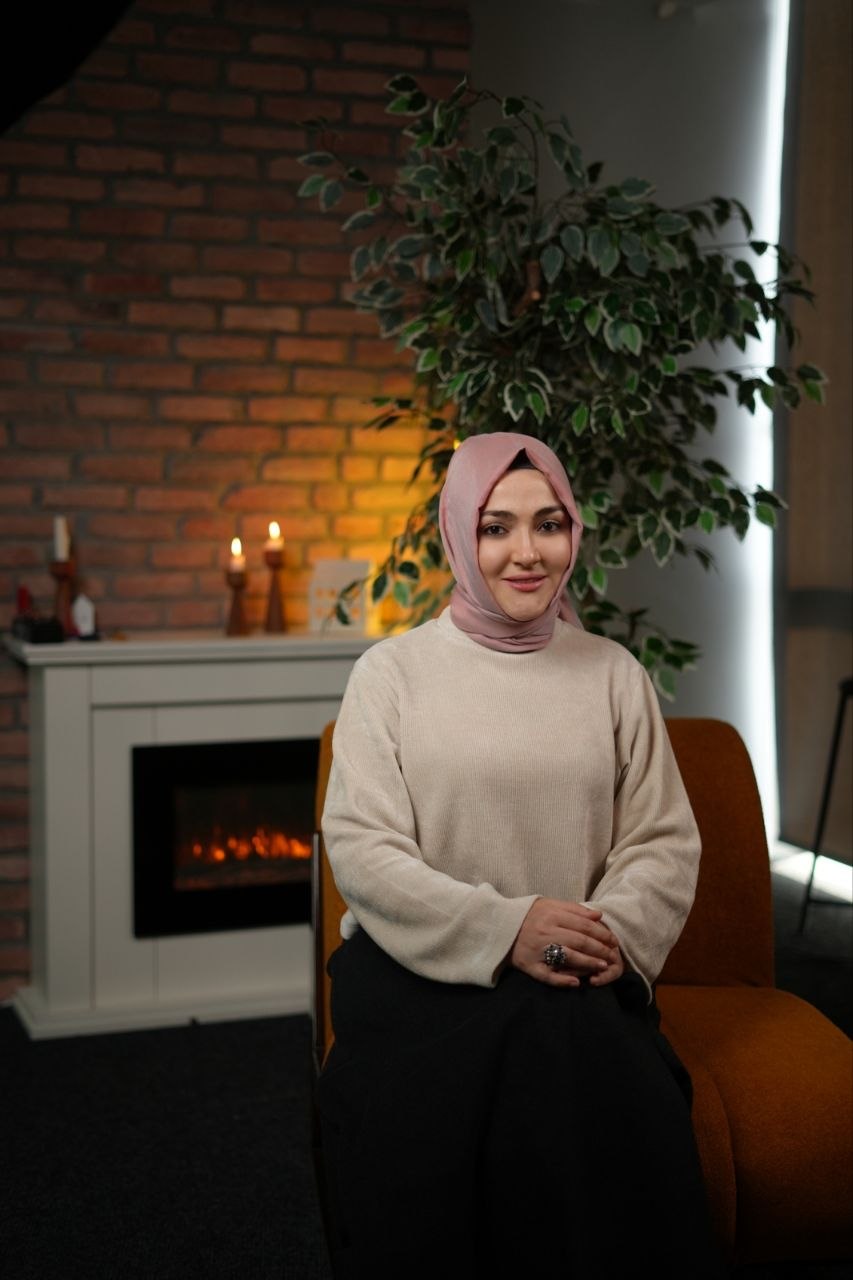 Kerime Melike Kaan, şömine önünde koltukta oturuyor
